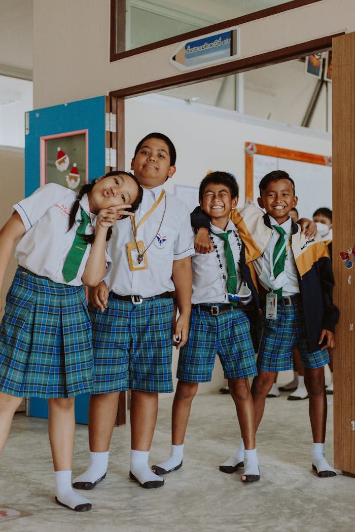 Happy group of students in school uniforms standing together in a classroom setting.